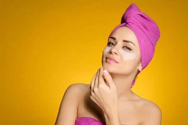 A woman with a towel on her head put patches under her eyes — Stock Photo, Image