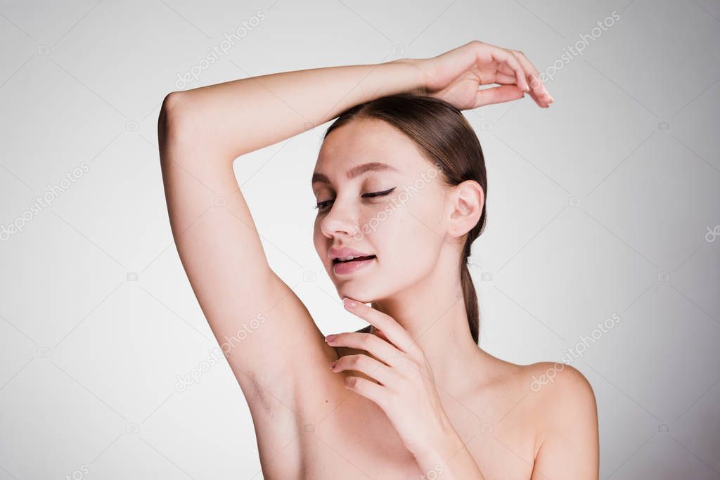 a surprised woman on a gray background shows her armpits