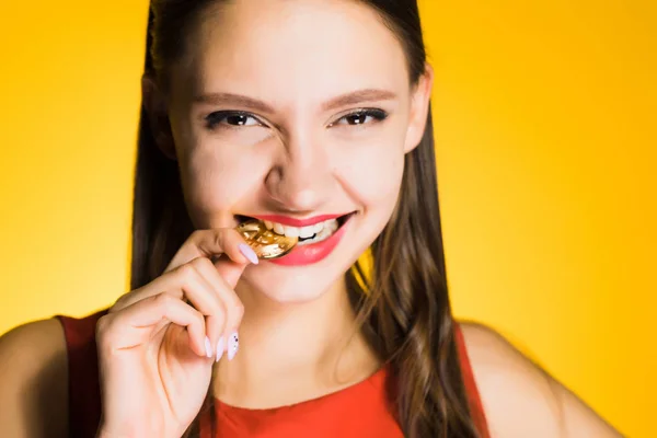 Happy woman bites the crypt on a yellow background — Stock Photo, Image