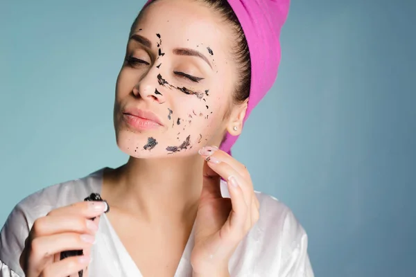 En kvinna med en handduk på huvudet tar bort masken från ansiktet — Stockfoto