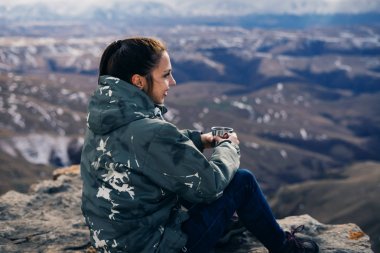kadın turist dağlar bir arka plan üzerinde çay içer