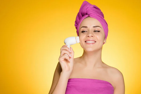 Woman with a towel on her head after showering brush her face for deep cleaning — Stock Photo, Image