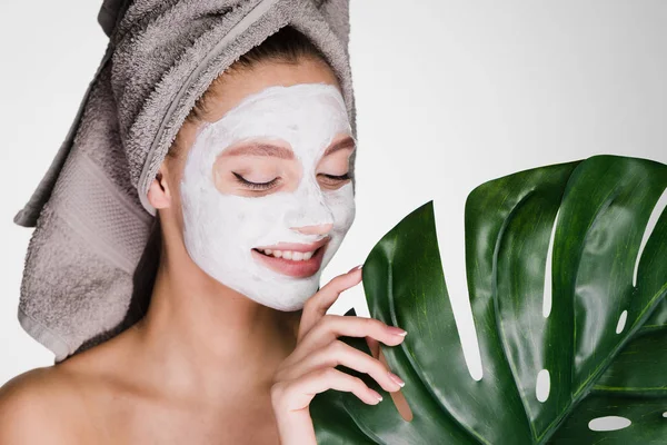 Gelukkige vrouw met een handdoek op haar hoofd een masker toegepast op haar gezicht — Stockfoto