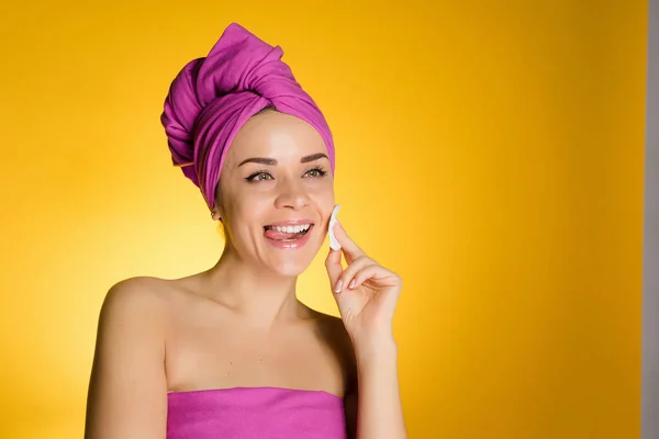 Glückliche Frau mit Handtuch auf dem Kopf entfernt Make-up mit einer Baumwollscheibe — Stockfoto