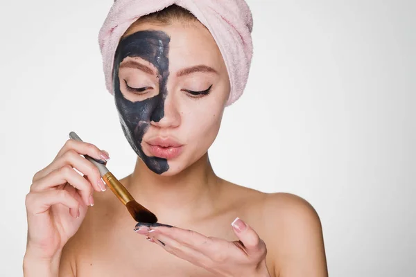 Женщина с полотенцем на голове после душа нанесите очищающую маску на лицо — стоковое фото