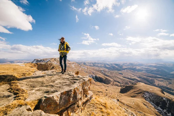 Turista mulher feliz com uma mochila em um fundo de montanhas — Fotografia de Stock