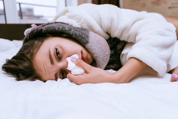 A sick woman with a warm scarf lies on the bed — Stock Photo, Image