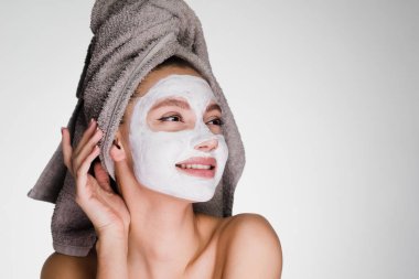 Kafasındaki bir havlu ile mutlu kadın yüzüne bir maske uygulanan
