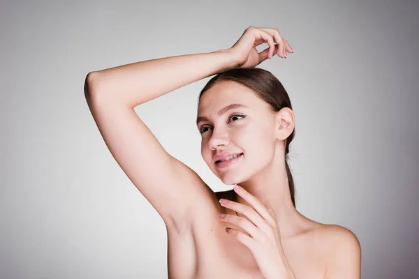 happy woman looks after armpits on a gray background