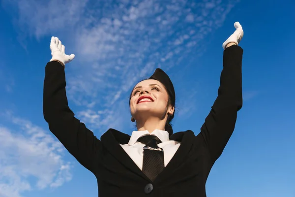 Letuška šťastná žena v uniformě na obloze na pozadí — Stock fotografie
