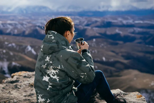 Turista mujer se sienta en el fondo de las montañas y bebe té —  Fotos de Stock