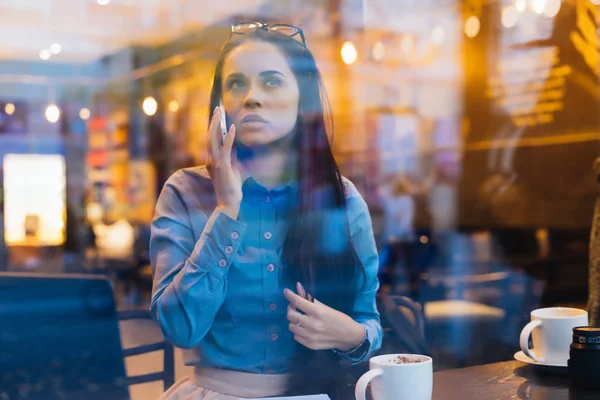 kadın pencerenin dışında bir kafede oturur ve telefonla konuşuyor