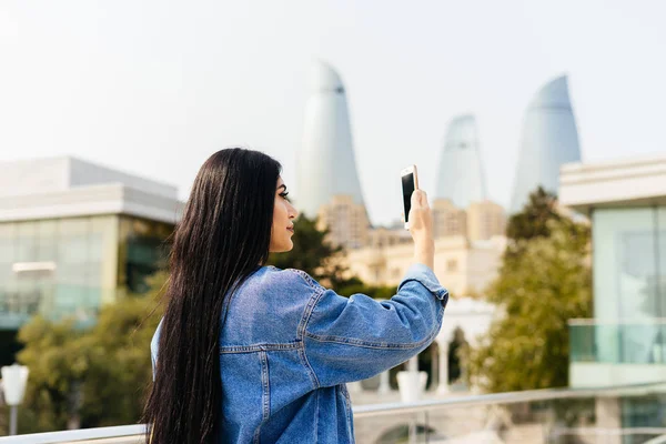stylish woman looking at phone on city background