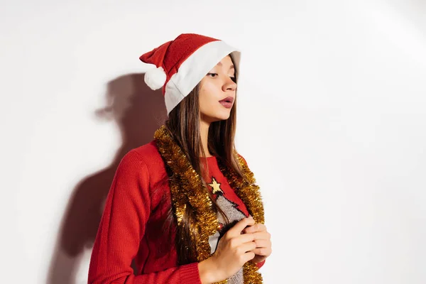 Συλλογισμένος γυναίκα σε ένα καπέλο Χριστουγέννων σε ένα γκρίζο φόντο — Φωτογραφία Αρχείου