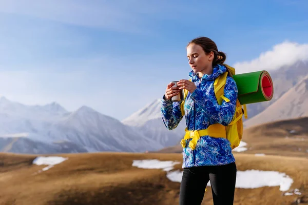 Turystyczna szczęśliwa kobieta pije herbatę na tle pięknych gór pokrytych śniegiem — Zdjęcie stockowe