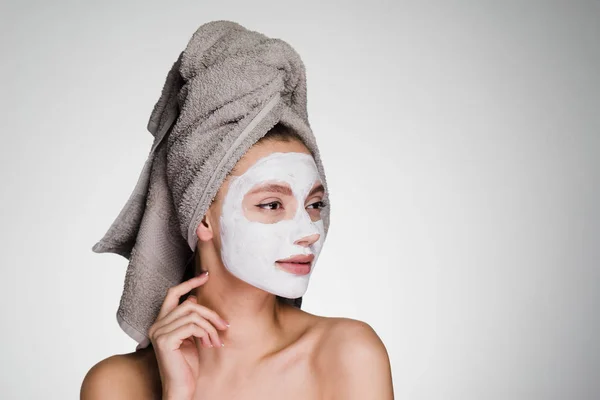 沉思的妇女在她的头毛巾在淋浴后涂抹洁面面膜 — 图库照片