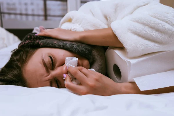 Nemocná žena leží na posteli a papírové ručníky — Stock fotografie