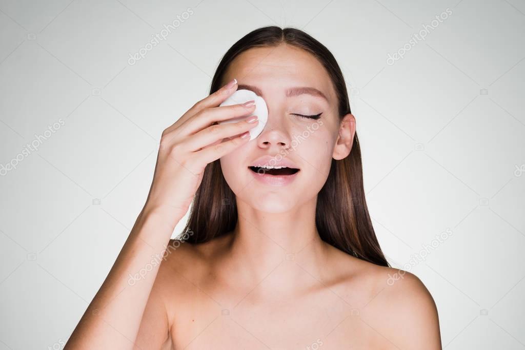 woman removes makeup from the eyes of a cotton ball