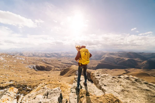 A woman tourist with a large backpack stands amid high mountains — Stock Photo, Image