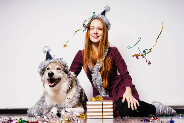 快乐的女人在节日帽旁边坐在狗的礼物背景 — 图库照片