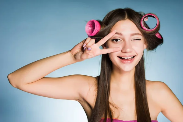 幸せな若い女の子表示カーラーの頭に 2 本の指を笑顔 — ストック写真