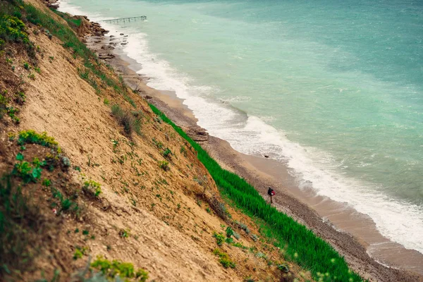 Вид сверху на бирюзовое море и белую пену, вдоль песчаного пляжа есть человек — стоковое фото