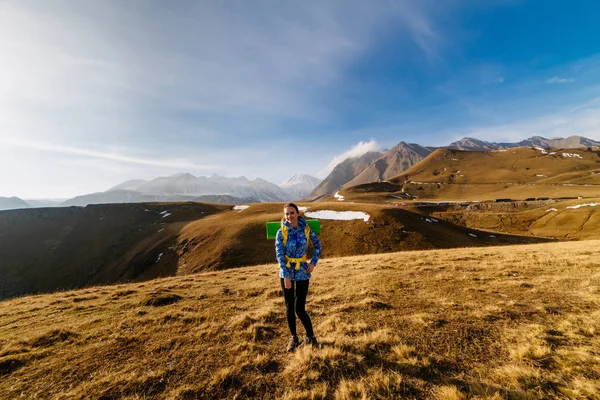 Щаслива жінка турист стоїть на тлі гір в сонячний день — стокове фото