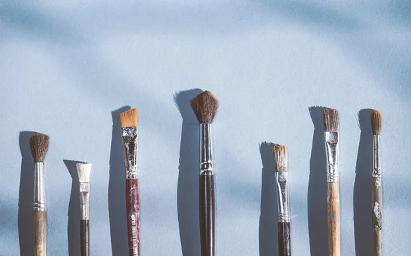 På blå ytan är konstnärliga penslar i olika storlekar — Stockfoto
