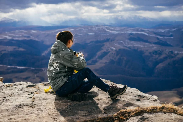Žena turistické leží na kopci a pije čaj na pozadí hor — Stock fotografie