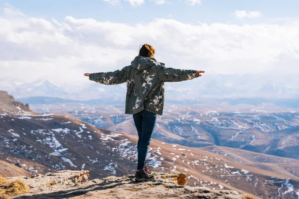 Ένα θηλυκό τουριστών στέκεται σε μια βουνοπλαγιά με φόντο βουνά σε μια ηλιόλουστη ημέρα — Φωτογραφία Αρχείου