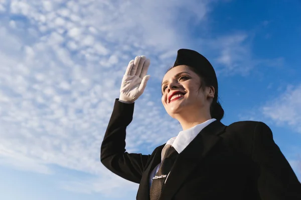 Счастливая стюардесса в форме на фоне неба — стоковое фото