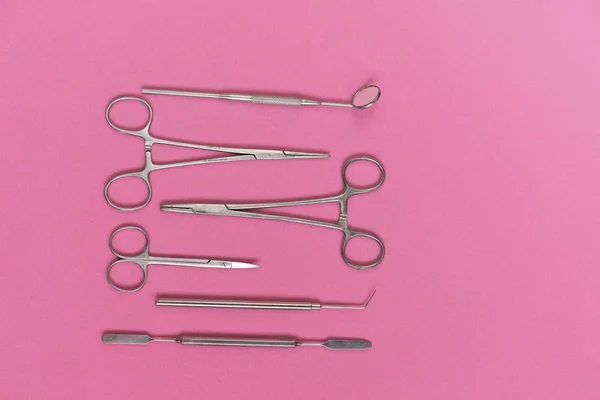 Op een roze achtergrond is een tandheelkundige instrument — Stockfoto