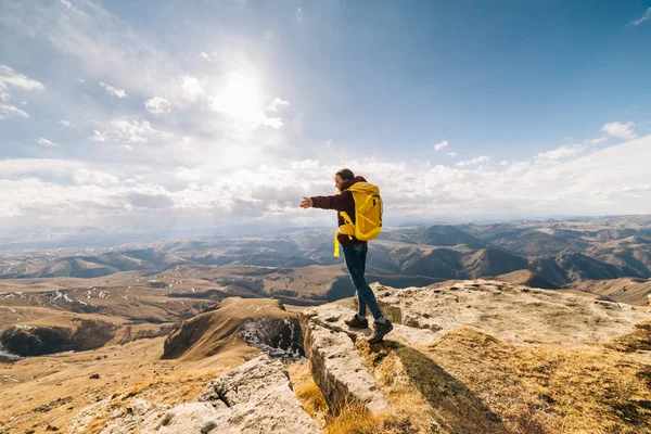 Kadın turist güneşli bir günde yüksek dağlar arka plan üzerinde bir sırt çantası ile duruyor — Stok fotoğraf