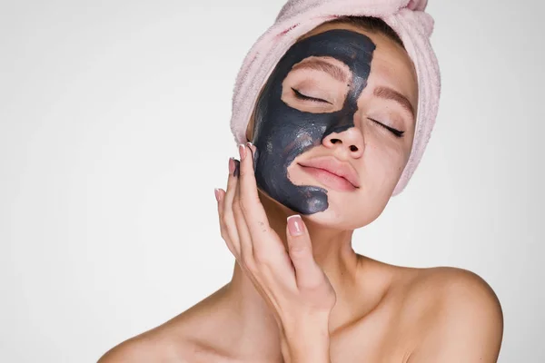 Zdumiony kobieta z ręcznikiem na głowie stosuje oczyszczanie maski na twarzy — Zdjęcie stockowe
