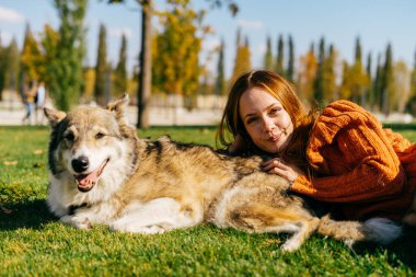 Köpeğiyle yürüyen parkta çimlere yatan kadın