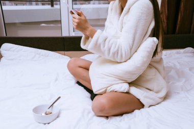 yatakta kahvaltı telefonu ararken oturan kadın