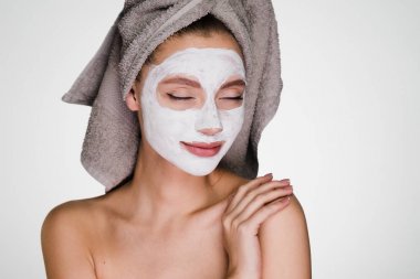 yüzünde bir maske duş sonra başında bir havlu ile şaşkın bir kadın