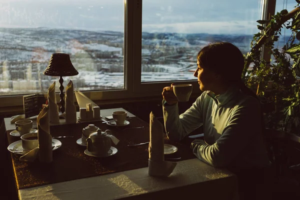 La mujer está sentada en un café y tomando té en el fondo de las montañas —  Fotos de Stock