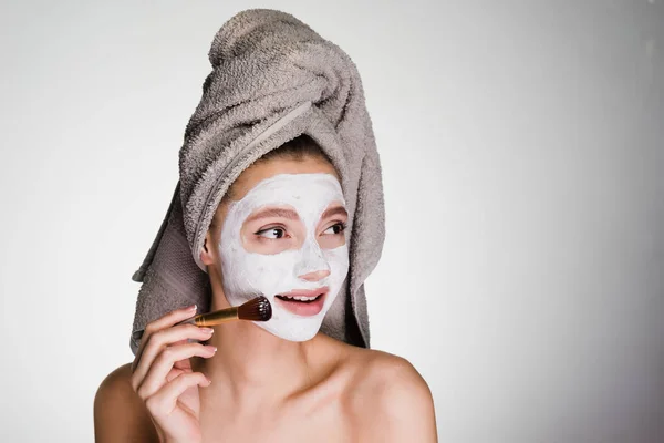 Szczęśliwa kobieta z ręcznikiem na głowie i z białą maskę na twarzy — Zdjęcie stockowe
