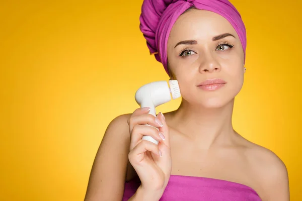 Woman with a towel on her head after showering her face with a brush for deep face cleansing — Stock Photo, Image