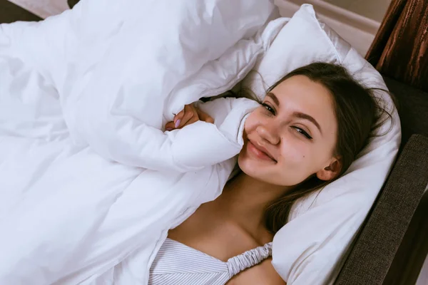 Mujer feliz se encuentra en la cama debajo de una manta — Foto de Stock