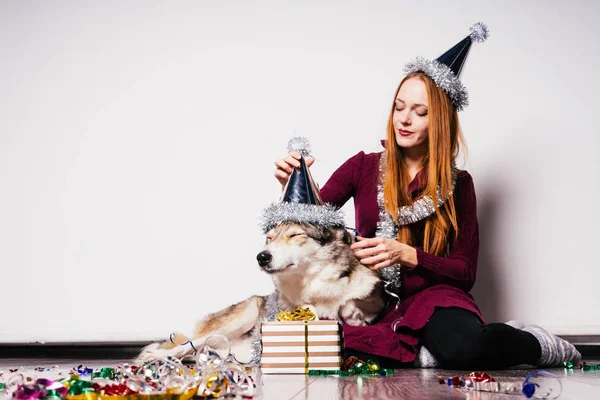 A woman in a festive hat sits next to a dog — Stock Photo, Image