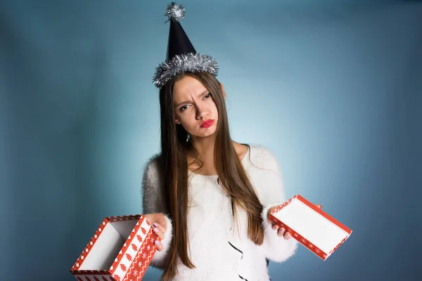 Расстроенная женщина в праздничной шляпе держит пустую коробку в руках — стоковое фото