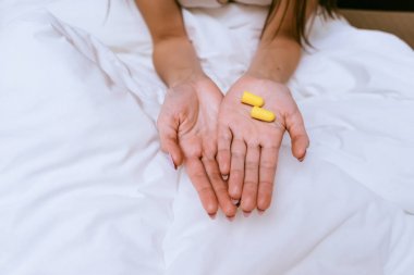 kadın yatakta oturuyor ve kulak tıkacı holding