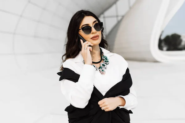 beautiful business woman speaks by phone on building background