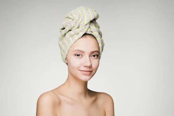 Una donna sorpresa con un asciugamano sulla testa su uno sfondo grigio — Foto Stock