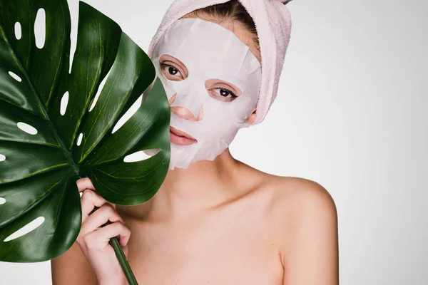 Γυναίκα με μια πετσέτα στο κεφάλι της μια μάσκα εφαρμόζεται στο δέρμα του προσώπου της — Φωτογραφία Αρχείου