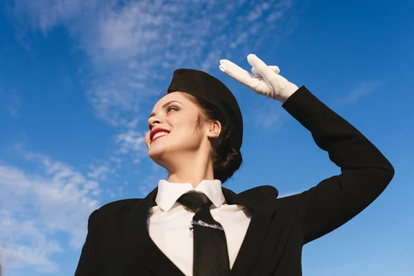 Femme heureuse hôtesse de l'air en uniforme sur fond bleu ciel Photo De Stock