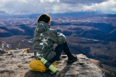 bir uçurum Dağları arka planda kadın turist oturur