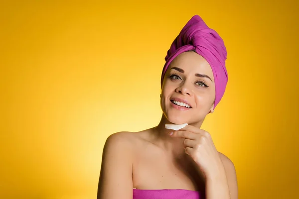 Ευτυχισμένη γυναίκα με μια πετσέτα στο κεφάλι της απογειώνεται το μακιγιάζ με ένα δίσκο βαμβακιού — Φωτογραφία Αρχείου